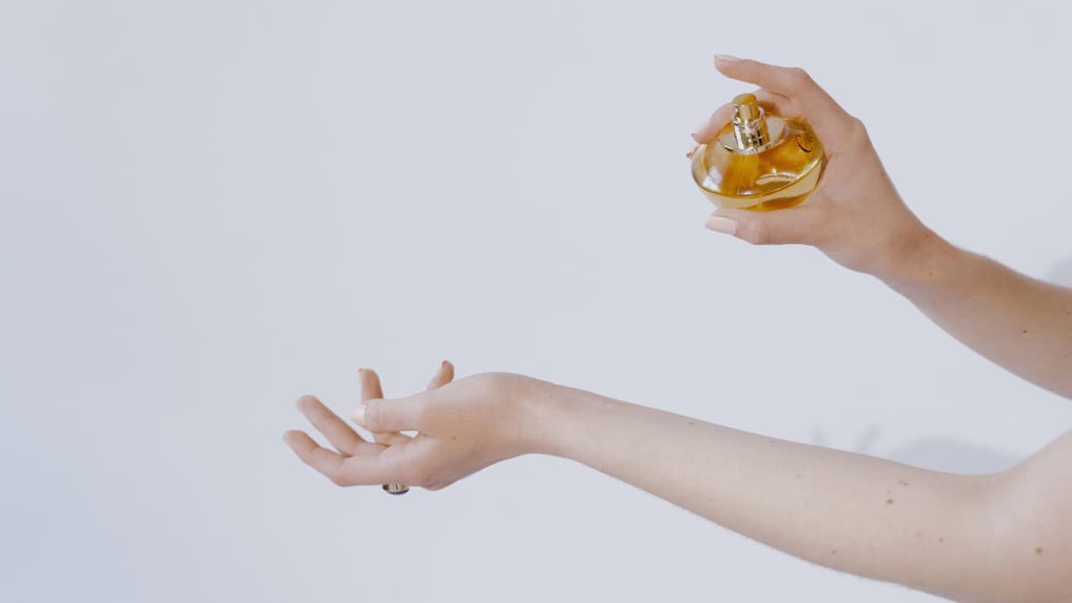 Frau sprüht sich mit Parfum ein 