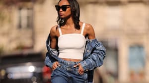 Frau trägt auf der Straße Jeans und Jeansjacke mit Ankle Boots