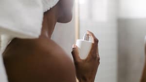 Frau sprüht sich mit Parfum ein