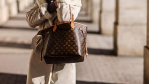 Frau in beigefarbenem Mantel mit Louis Vuitton Tasche