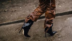 Frau trägt braune Lederhose und schwarze Lack Stiefel Streetstyle