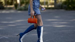 Frau trägt Jeans Stiefel und Jeansrock orangene Tasche Streetstyle