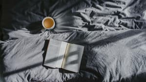 Bett mit Tasse Kaffee Bettdecke und Buch