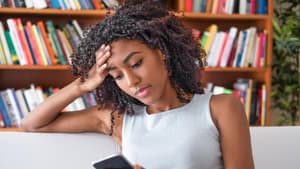 Frau hält Handy zu Hause in der Hand auf dem Sofa