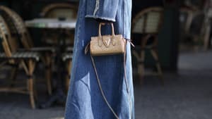 Frau trägt Jeansmantel Jeansschuhe Streetstyle goldene Tasche