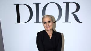 Maria Grazia Chiuri sitzt vor Dior Schild