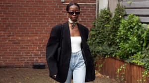 Eine Frau trägt eine blaue Jeans und einen schwarzen Blazer