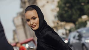 Paris Fashion Week Streetstyle Frau trägt schwarzes Kleid mit Kapuze