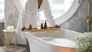 Frau im Bademantel stellt ein Tablett auf die Badewanne