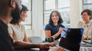 Vier Kollegen sitzen an einem Tisch und lachen