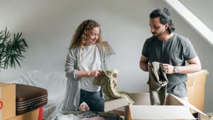Paar steht vor einer Kiste und sortiert Kleidung aus