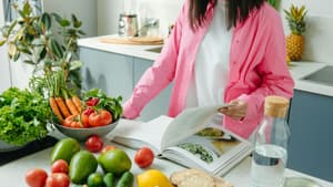 Frau kocht vegan mit Kochbuch