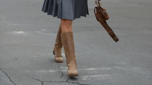 Frau spaziert mit braunen Stiefel über die Straße