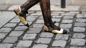 Frau trägt Ballerinas in  Gold und Schwarz