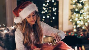 Frau mit Weihnachtsmütze packt ein Geschenk auf dem Sofa ein