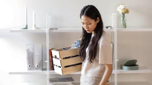 Frau geht mit einer Holzkiste durch ihre Wohnung