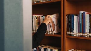 Frau greift in ein Bücherregal