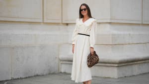 Frau in weißem Kleid und Leo-Tasche