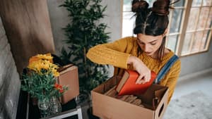 Frau legt ein rotes Buch in eine Kiste aus Pappe 