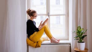 Frau liest ein Buch auf der Fensterbank