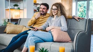 Paar sitzt auf der Couch und guckt Fernsehen