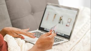 Frau vor dem Laptop mit einer Kreditkarte in der Hand