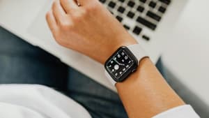 Frau am Laptop schaut auf Uhr