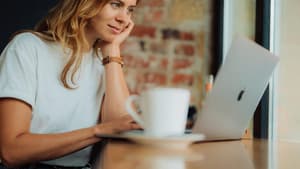 Junge Frau sitzt mit ihrem Laptop in einem Café