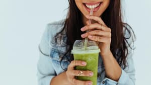Eine Frau trinkt einen grünen Smoothie