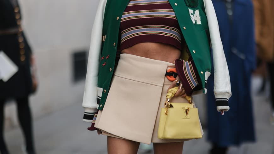 Frau trägt einen kurzen Minirock und eine Designer-Handtasche von Louis Vuitton