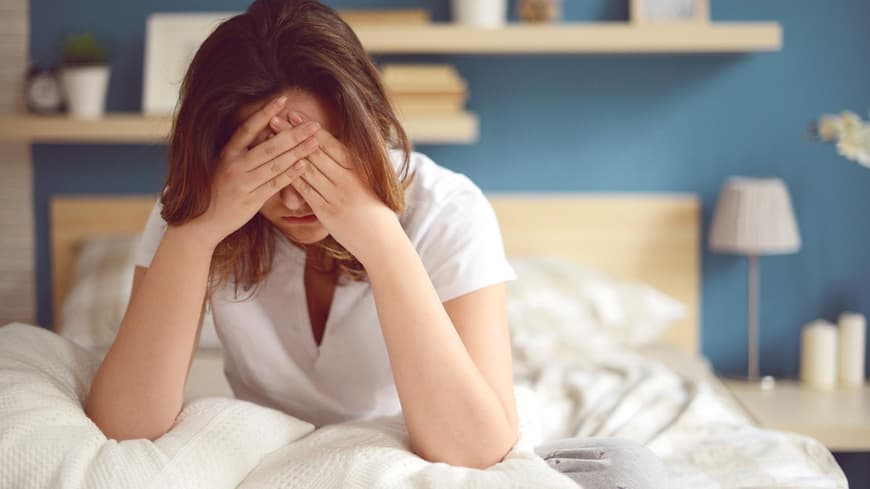 Eine Frau sitzt traurig in ihrem Bett