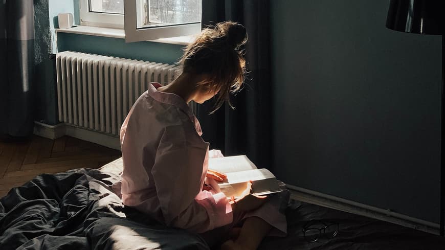 Frau liest Buch auf Bett