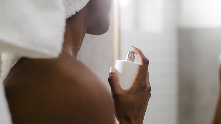 Frau sprüht sich mit Parfum ein