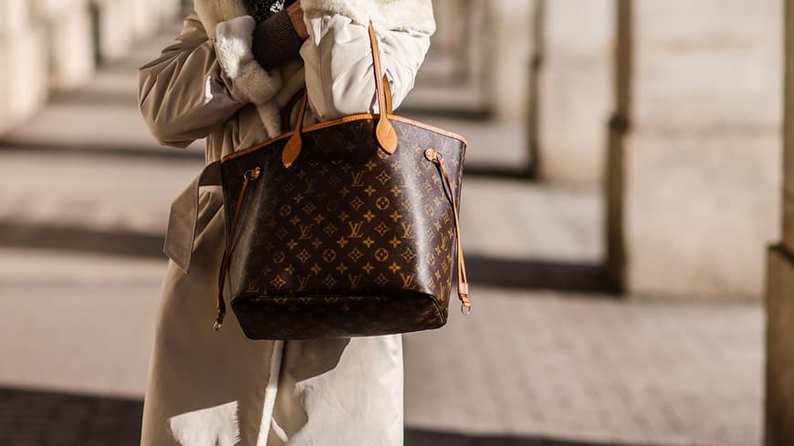 Frau in beigefarbenem Mantel mit Louis Vuitton Tasche