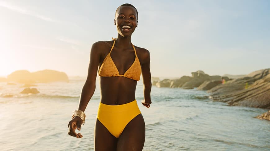 Frau im Bikini zu Fuß am Strand gelb