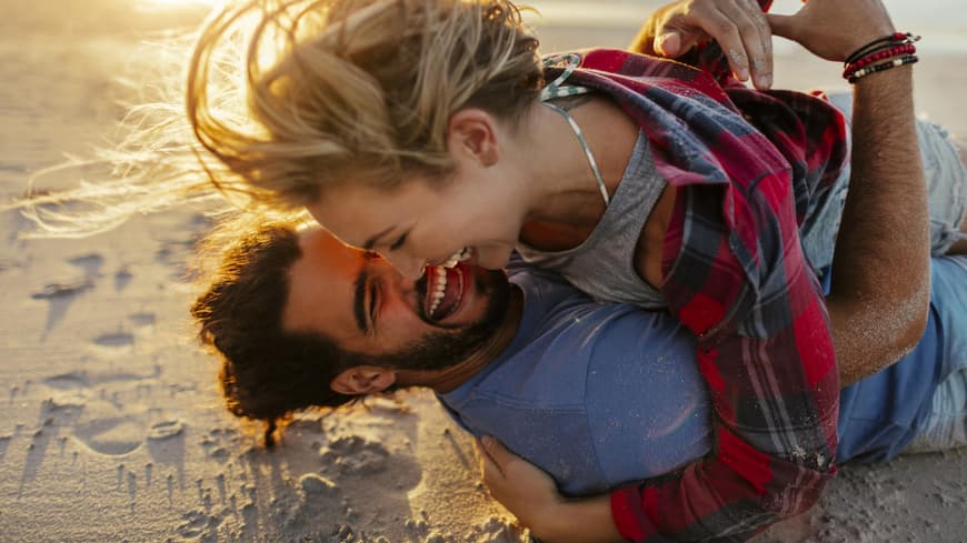 Frau und Mann lachen am Strand