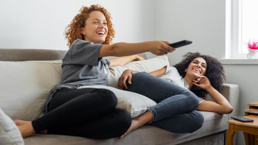 Fernsehen schauen zwei Frauen Couch Fernbedienung