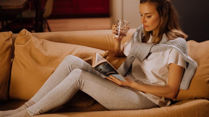 Frau liest Buch auf dem Sofa