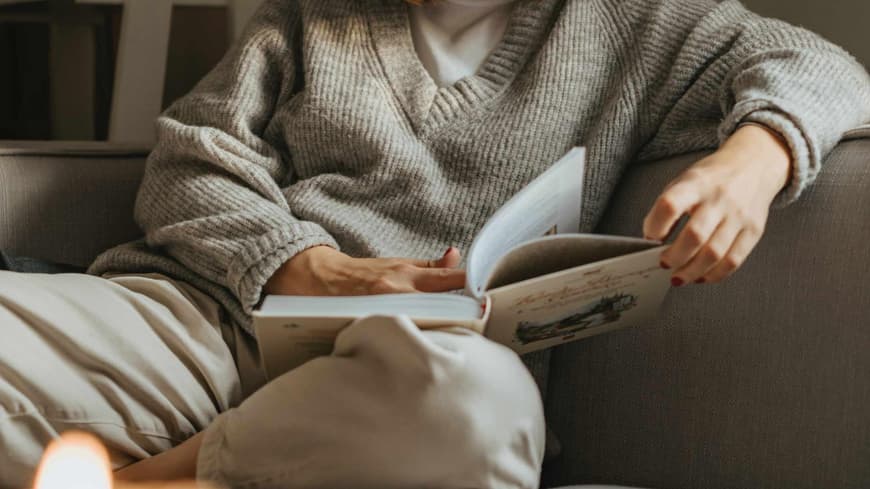 Frau sitzt auf Sofa und liest