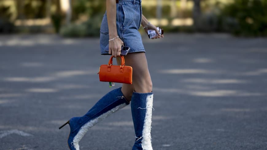 Frau trägt Jeans Stiefel und Jeansrock orangene Tasche Streetstyle