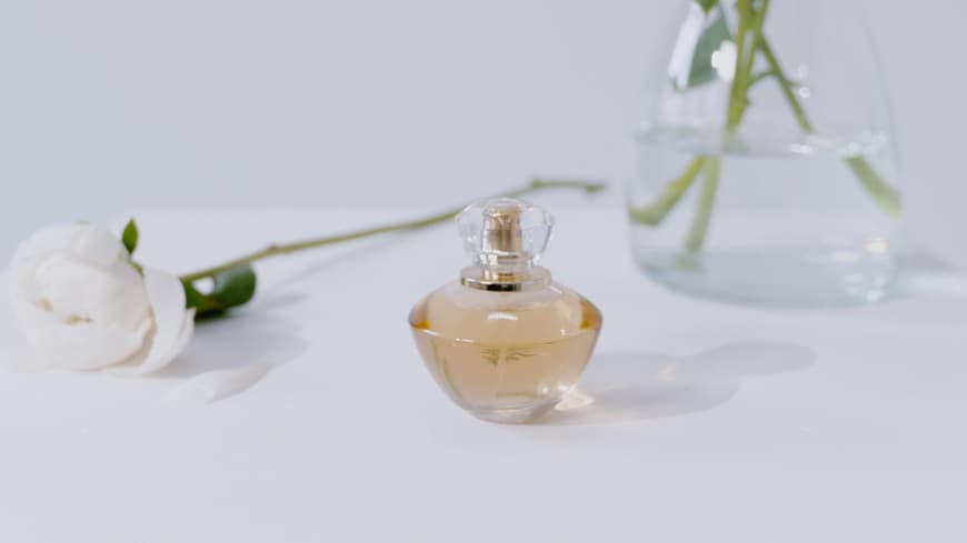 Parfum Flakon vor Vase mit Blumen