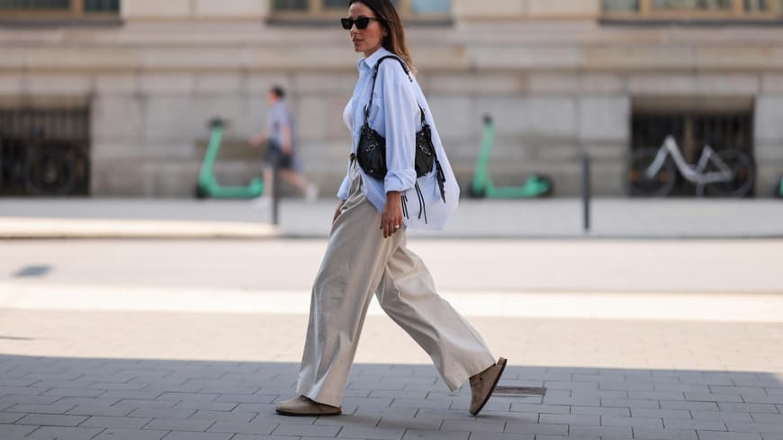 Frau trägt Birkenstocks, eine weiße Bluse und eine Leinenhose