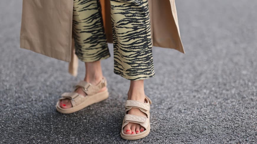 Frau trägt beige Sandalen und eine gemusterte Hose