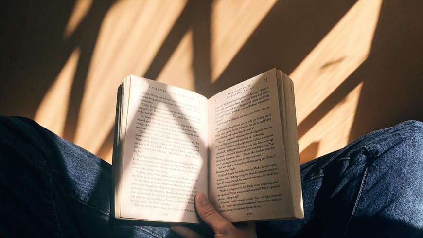 Person sitzt auf Boden und liest Buch