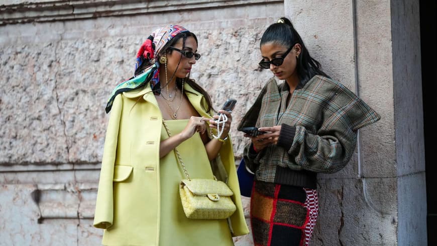 Zwei stylische Frauen schauen auf ihr Handy