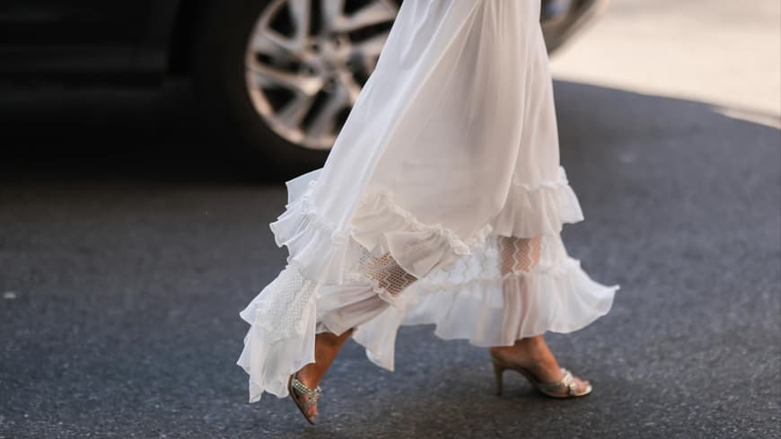 Frau trägt silberne Schuhe zum weißen Kleid