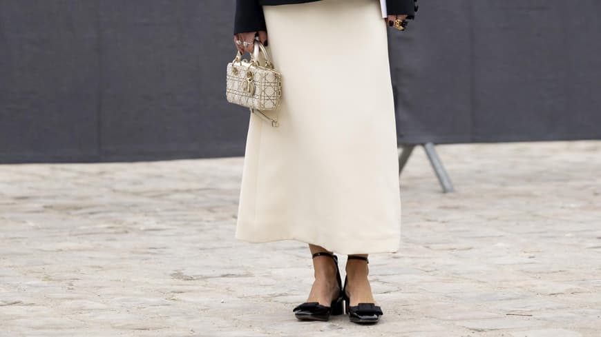Eine Frau trägt einen langen weißen Rock und einen schwarzen Blazer
