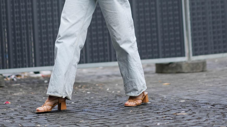 Frau in hellem Look mit braunen Sandalen