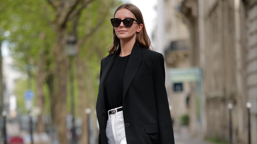 Frau trägt schwarzen Blazer und weiße Jeans