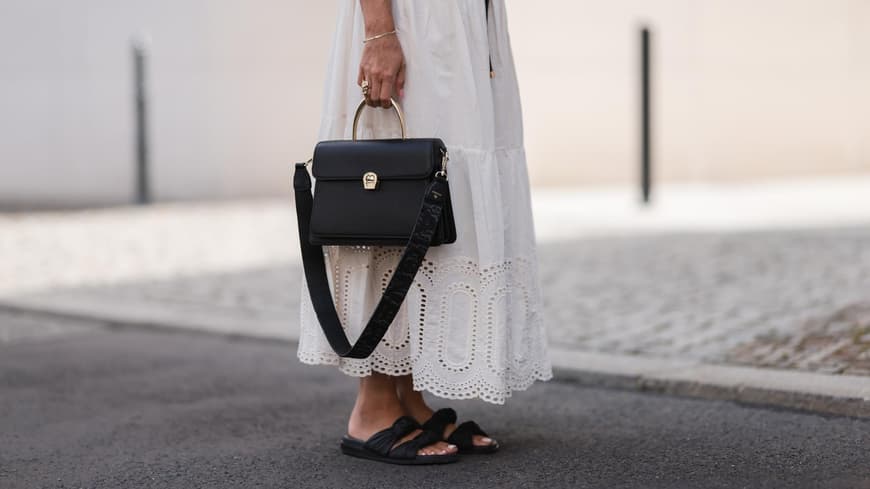 Eine Frau trägt ein weißes Kleid und schwarze Sandalen